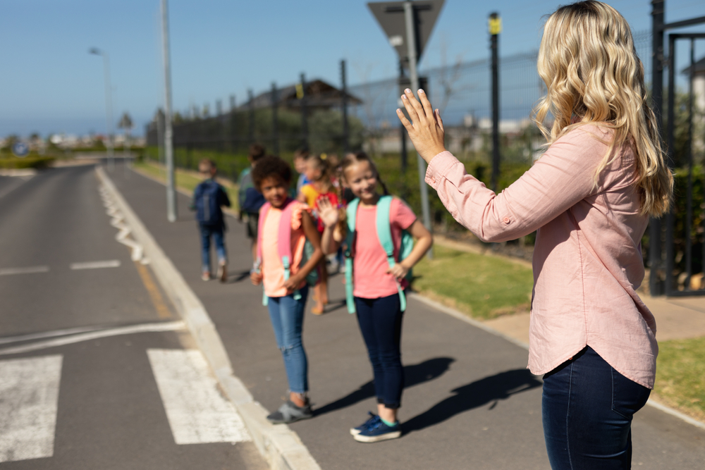 femme avec des elves qui apprennent a traverser une route sur les bandes blanches